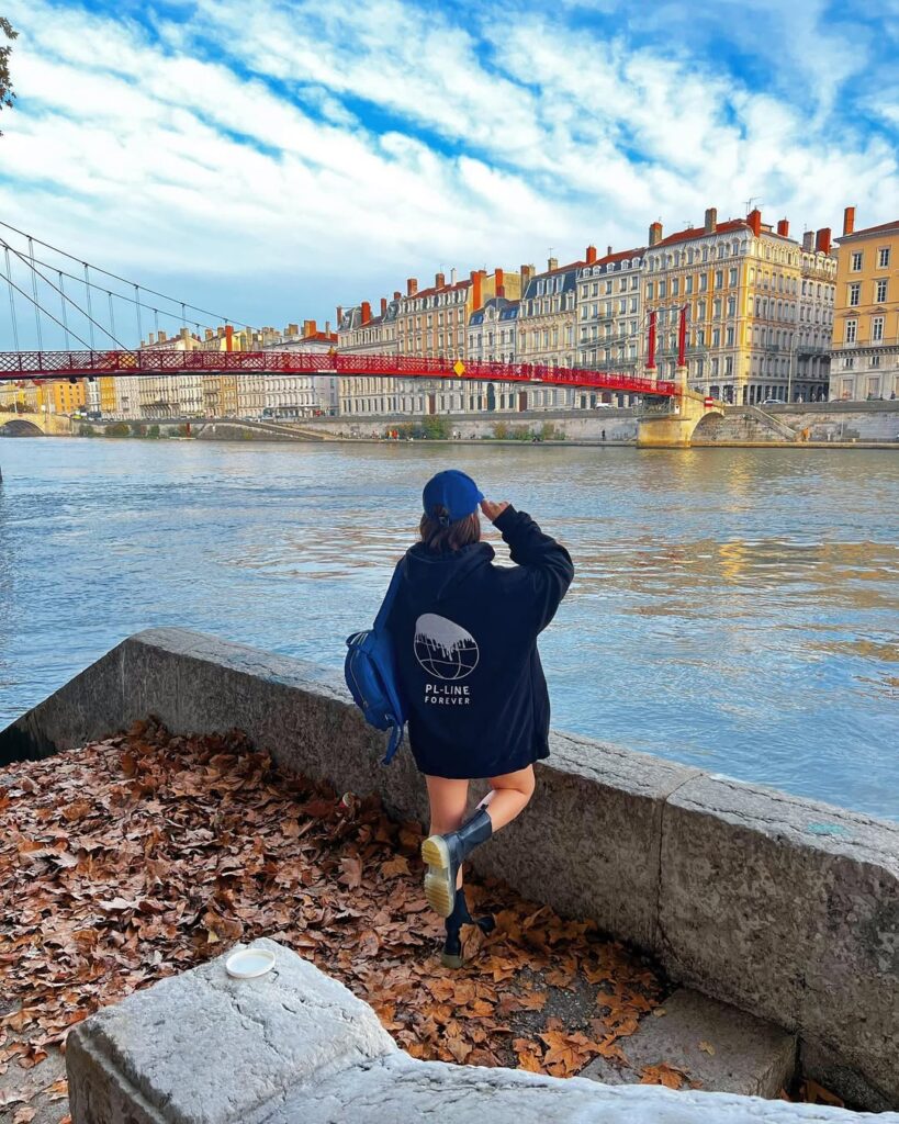 A serene view of the Saône River with Lyon’s colorful buildings reflected in the water. Lyon travel guide and weed laws in France.