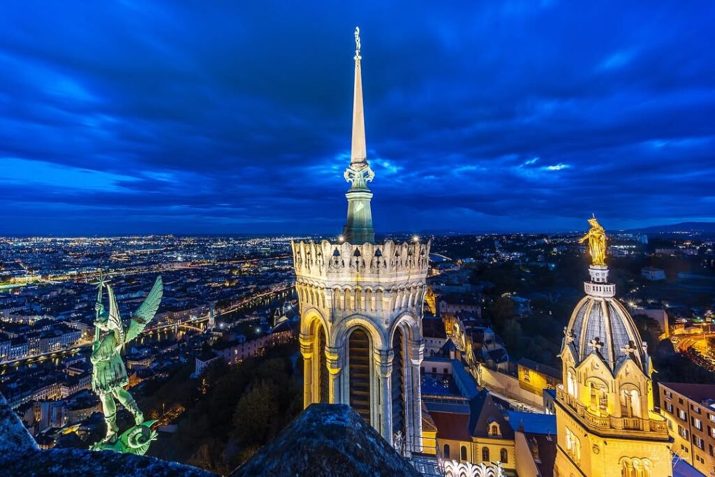 A sunset view of Lyon’s Basilica of Notre-Dame de Fourvière, with the city bathed in golden light. 