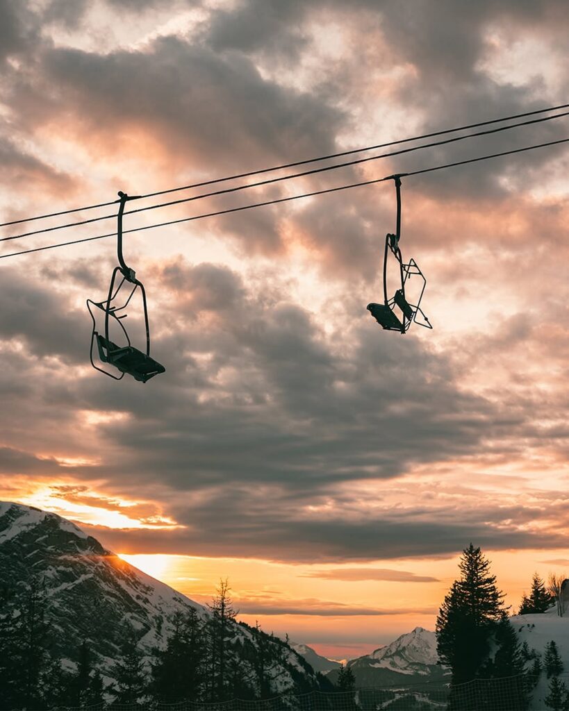 A sunset view of Morzine, travel guide and weed laws, with the mountains bathed in golden light and the town’s twinkling lights creating a cozy atmosphere.